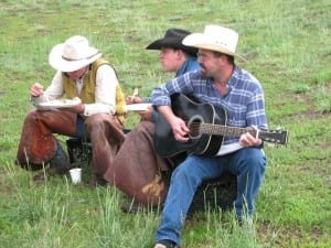 Man playing guitar while sitting with wranglers.