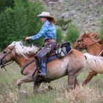 CM Ranch - Two riders galloping on horseback.