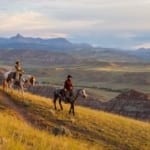 CM Ranch - two horseback riders on a hill overlooking mountains.