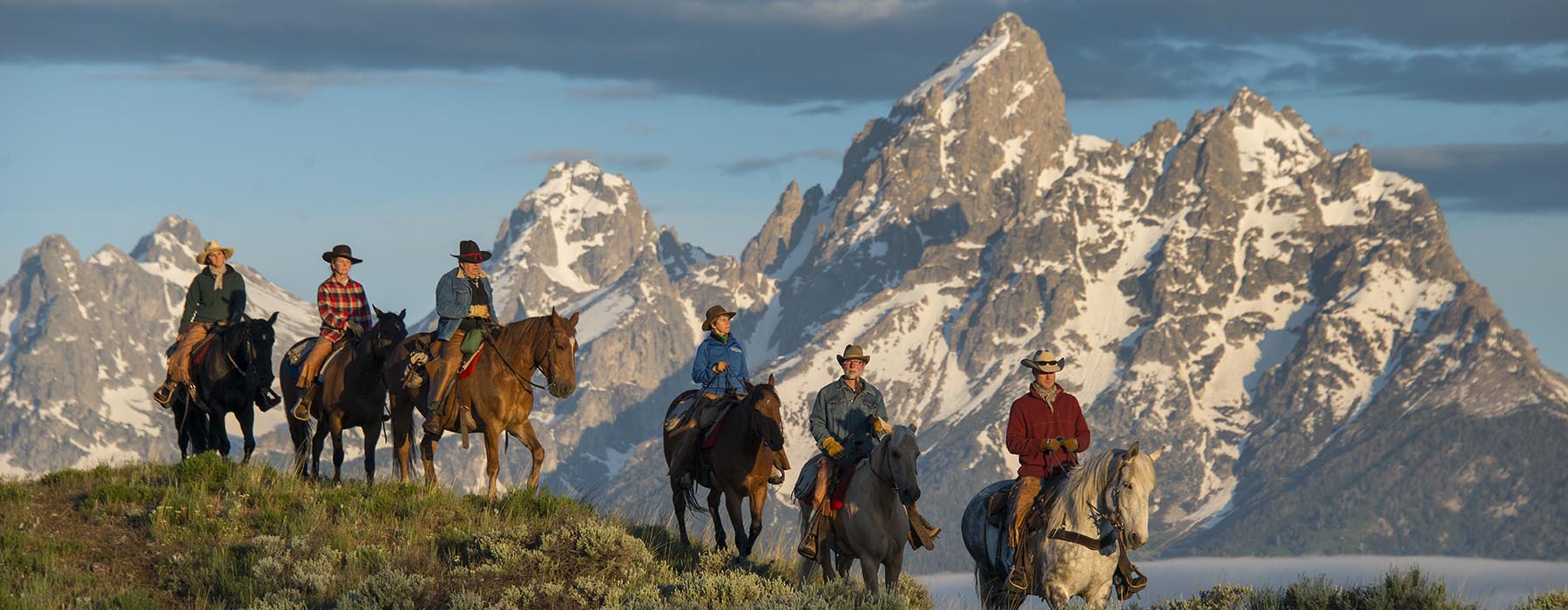 Horseback riders overlooking mountains.