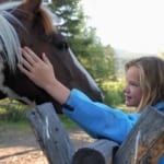 Moose Head Ranch - Young girl petting a horse.