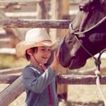 Red Rock Ranch - young boy petting a horse.
