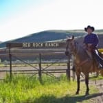 Red Rock Ranch - rider next to the ranch sign. Text: Red Rock Ranch.