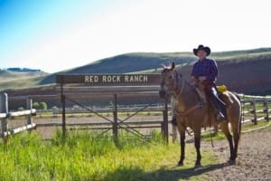 Red Rock Ranch - rider next to the ranch sign. Text: Red Rock Ranch.