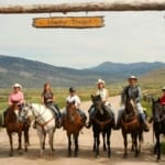 Red Rock Ranch - group on horseback under the ranch gate.