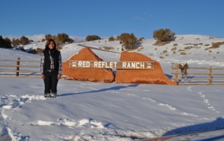 Rancher next to Red Reflet Ranch sign in winter.