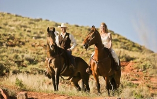 Bride and Groom riding horses in the hills.