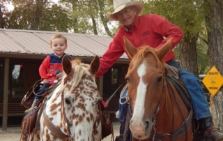 Grandfather and youngster on horses.