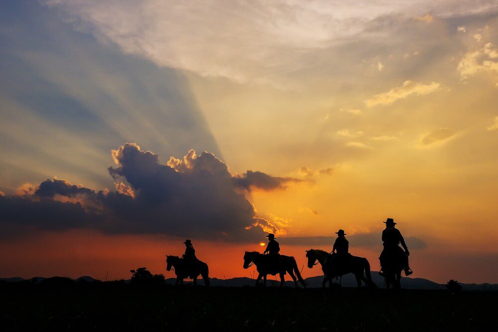 Photo of a group of people riding horses at sunset: corporate retreat ideas