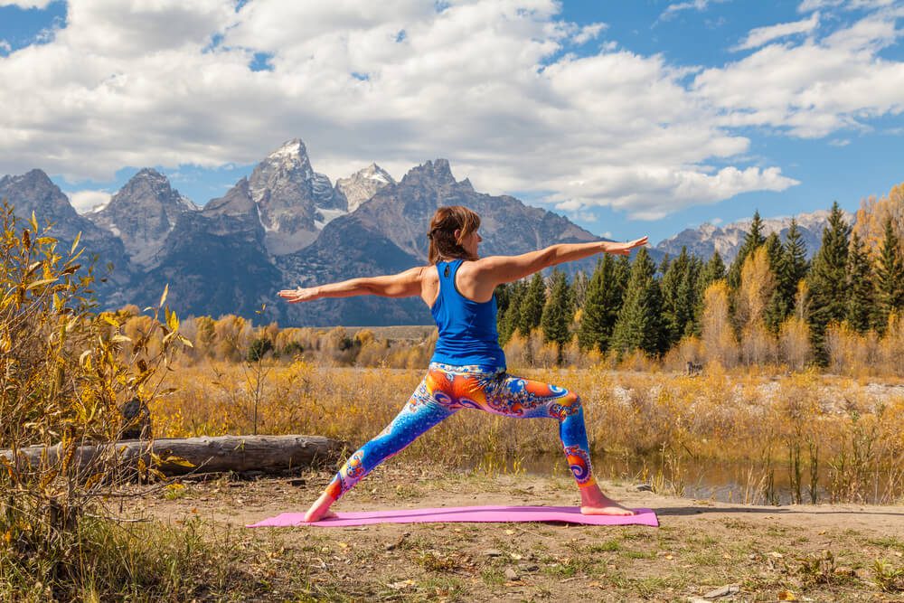 Woman doing yoga in front of the mountains during a wellness retreat in Wyoming