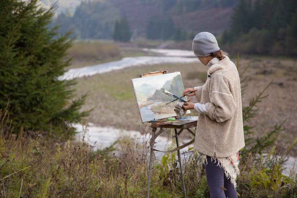 Person painting a river during a specialty week at dude ranches